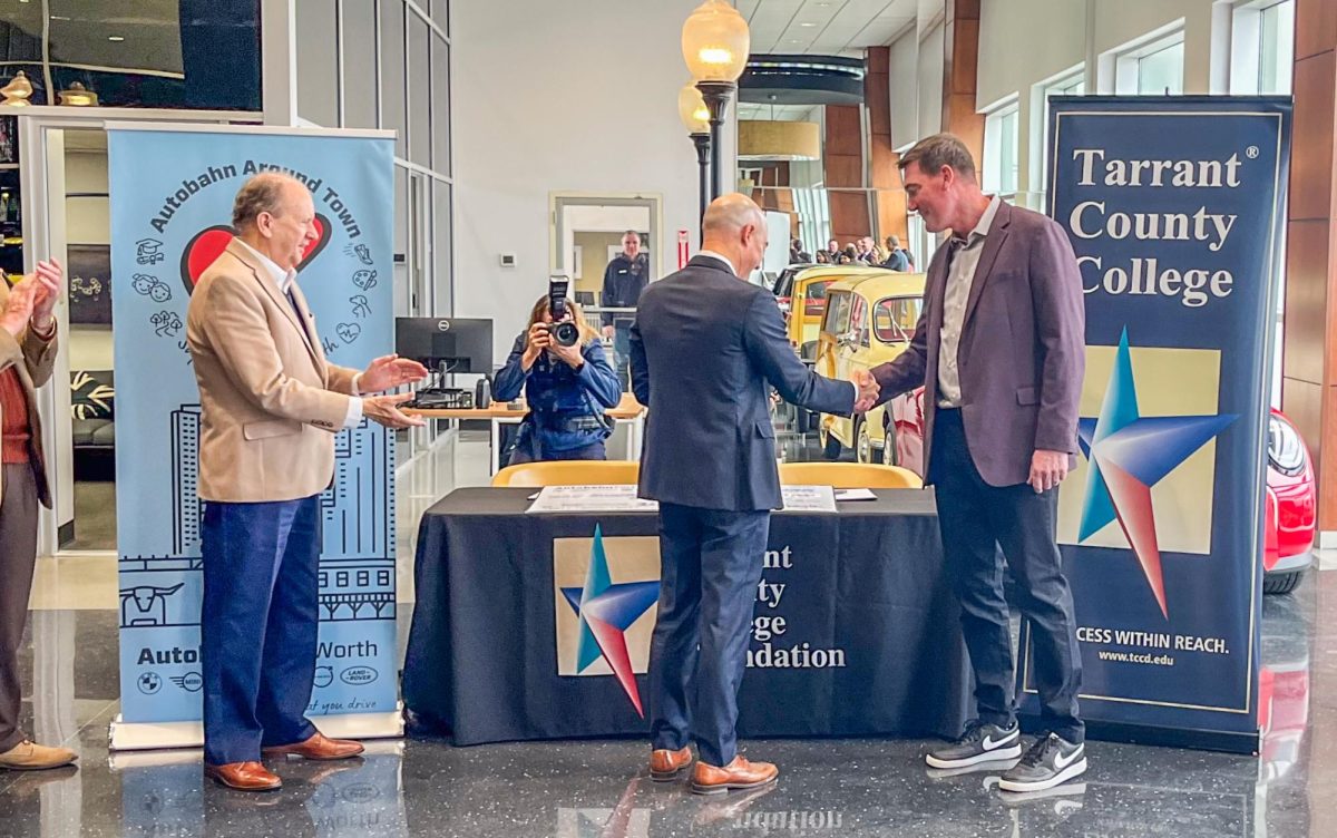 Board member Ken Barr, Autobahn Fort Worth president Brendon Harrington and South Campus president Dan Lufkin shake hands after signing the scholarship check at a celebration hosted at the dealership on Feb. 21.  