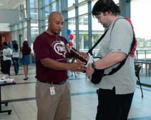 TR Campus student development associate Lionel Bailey assists TR student Chris Twitty with a Guitar Hero lesson during the Rock Enroll event Aug. 6. Martina M. Treviño/The Collegian