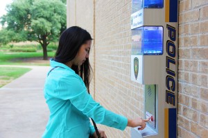 Student Emily Sayavong uses one of the blue boxes scattered around NE Campus to call a police officer for assistance. Students can use the box if they have car trouble, lose their keys or need help.  Photo by Zach Estrada/The Collegian