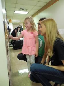 Astrid Halbach shows parents Sean and Marisa her caterpillar made from construction paper and leaves. The April 24 reception allowed Children’s Center students to show off their artwork.  Photo by Victor Henderson/The Collegian 