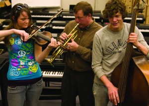 Brook and Caleb, left and right, are two of 10 children in the musical Wallace family. Paul Wallace, center, spends his days as a tax accountant and busy father to his family. All three and two other members of the family find time to play together in South’s jazz ensemble.  Jennifer Covington/The Collegian
