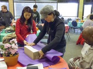 Hye Sookan, left, and Patty Carlon help wrap a package for a NE Student Leadership Academy project recently. Photo by Hope Sandusky/The Collegian