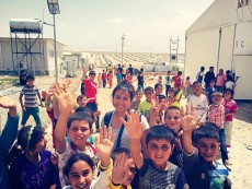TR student Leslie Fernandez stands with children in an Iraq refugee camp in May. She helped her father put on shows for the children.Photo courtesy Leslie Fernandez