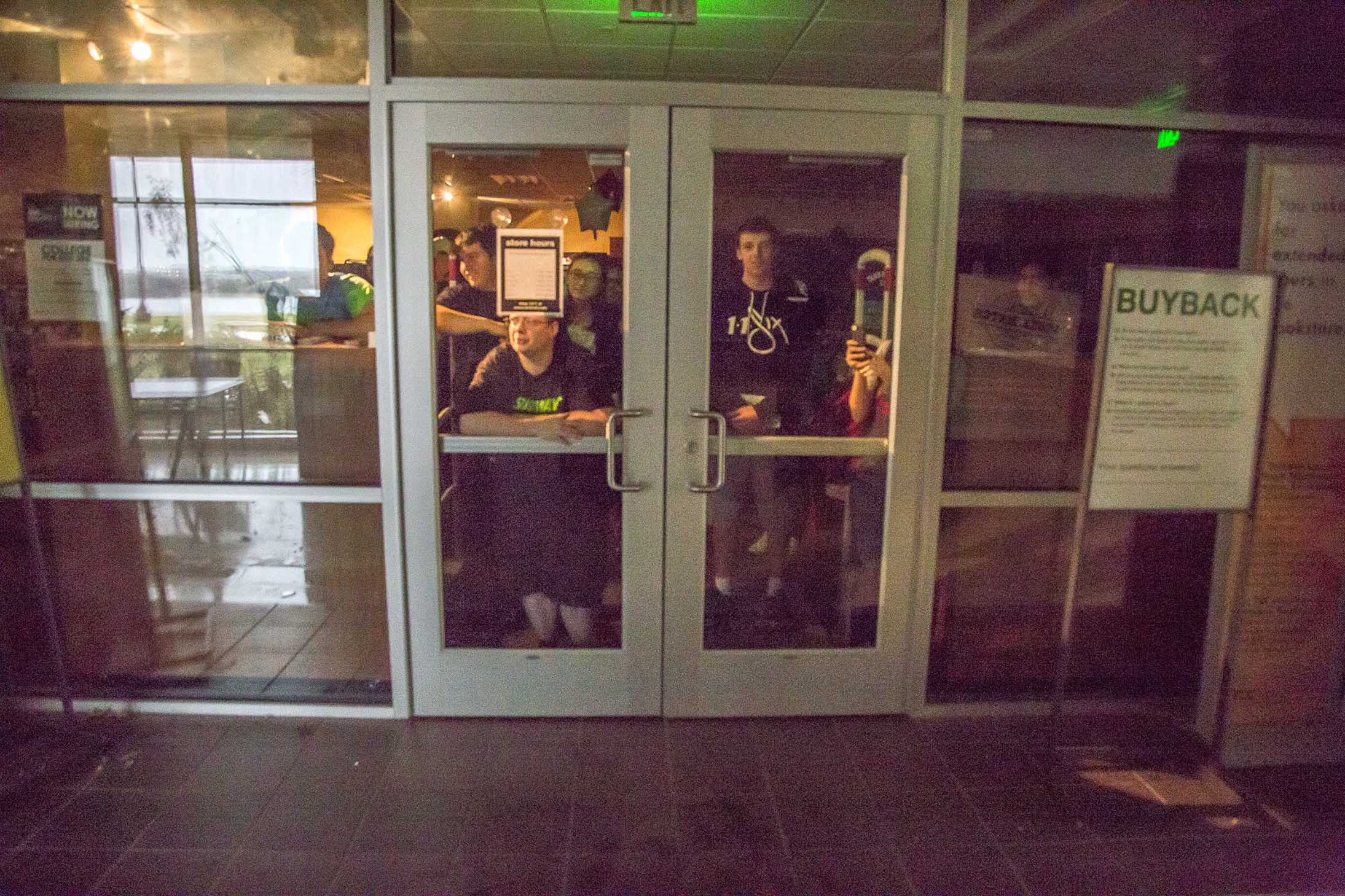 NW students watch from behind locked doors in the WSTU bookstore as maintenance staff clear the halls of broken glass.
