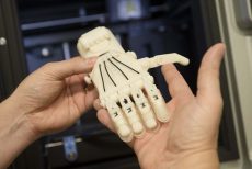 Brooke Thompson holds a 3-D printed hand to show one of the many objects that can be printed with this new technology. 