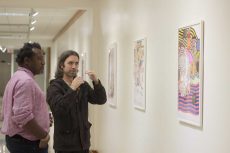 SE instructional assistant Christopher Blay and artist Adam Palmer review the exhibit.