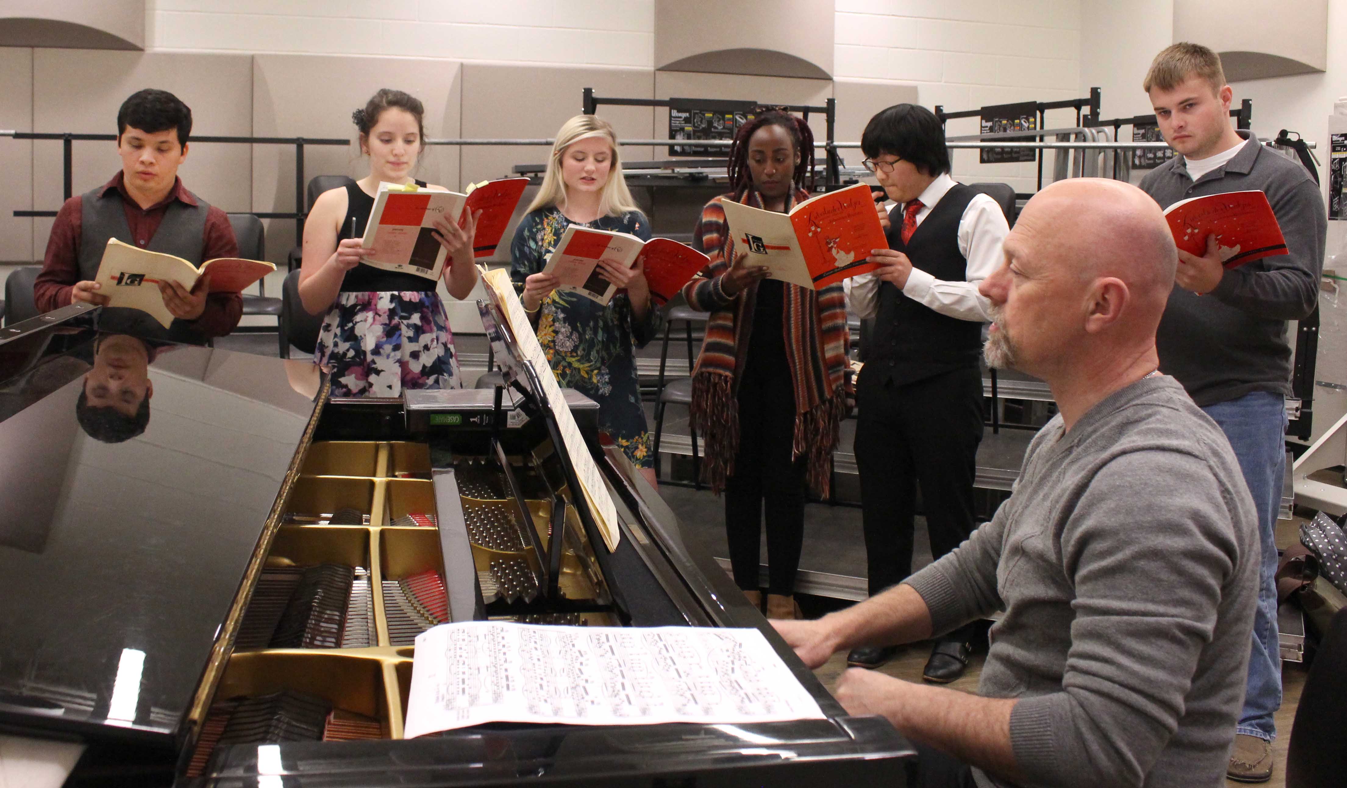 NE music instructor and choir director Stan Paschal works with students as they learn their parts for a song they will perform during the Dessert Theater.