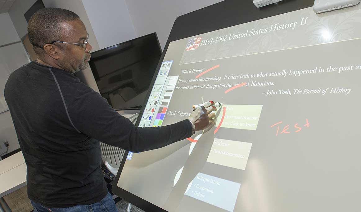 NE media services coordinator Cedric Hights demonstrates the moveable, interactive board that displays projected images that instructors can mark up using special tools to make classes more interactive.