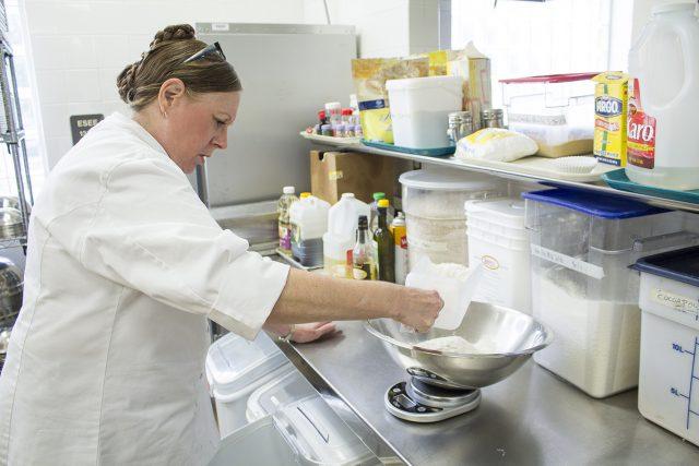 SE culinary arts instructor Alison Hodges uses a scale to measure flour in one of the kitchens in the ESEE building before one of her classes.