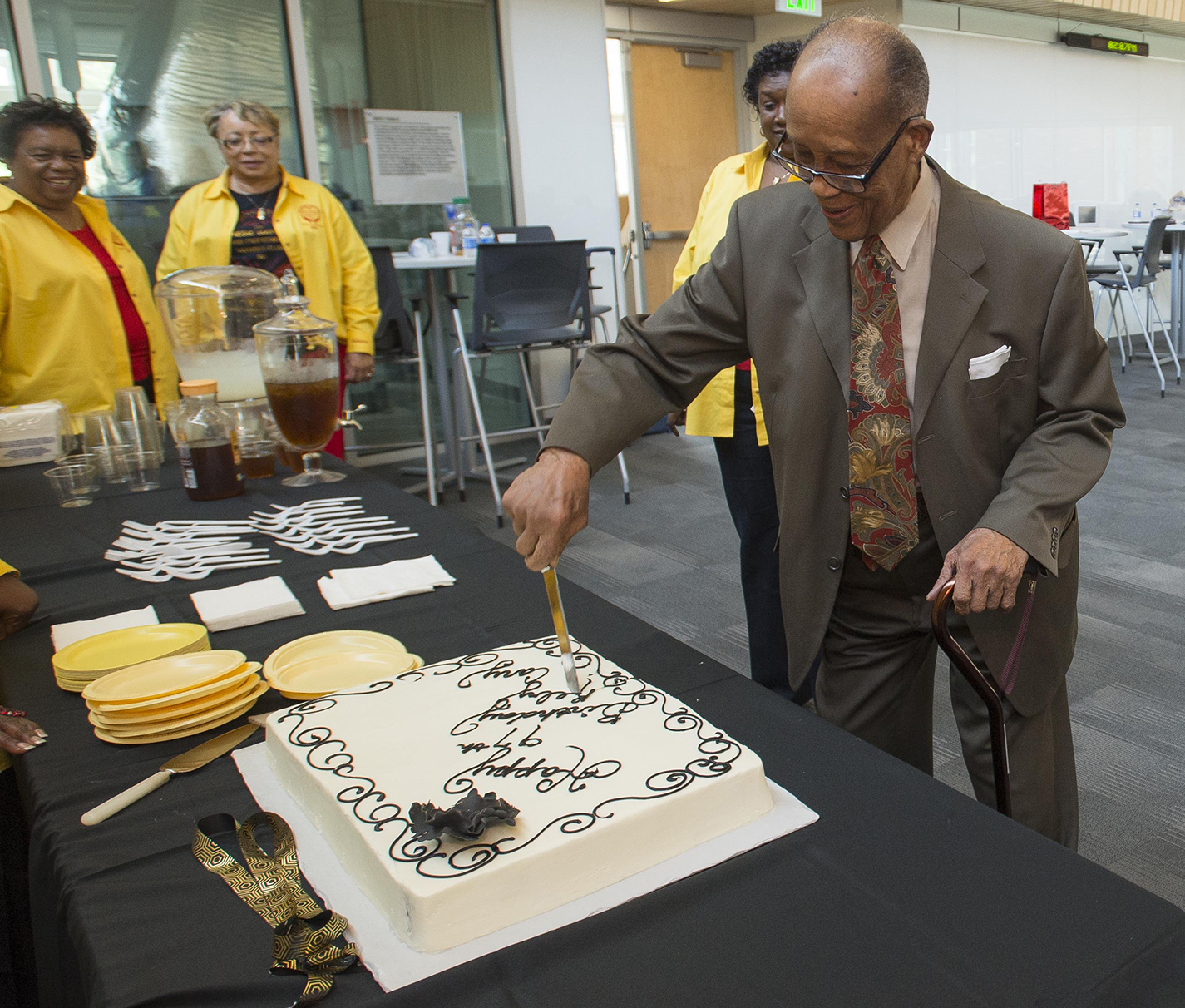 After speaking with attendees, former South professor Reby Cary cuts the cake to honor his 97th birthday Sept. 9.