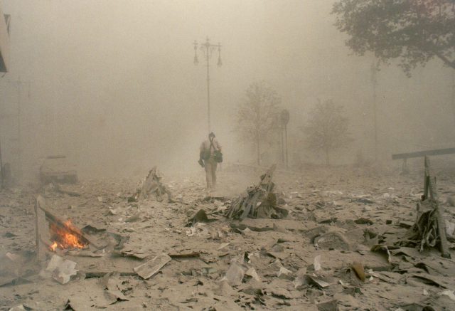 Debris burns as a man walks down Park Row moments after the South Tower of the World Trade Center collapsed on Sept. 11, 2001.