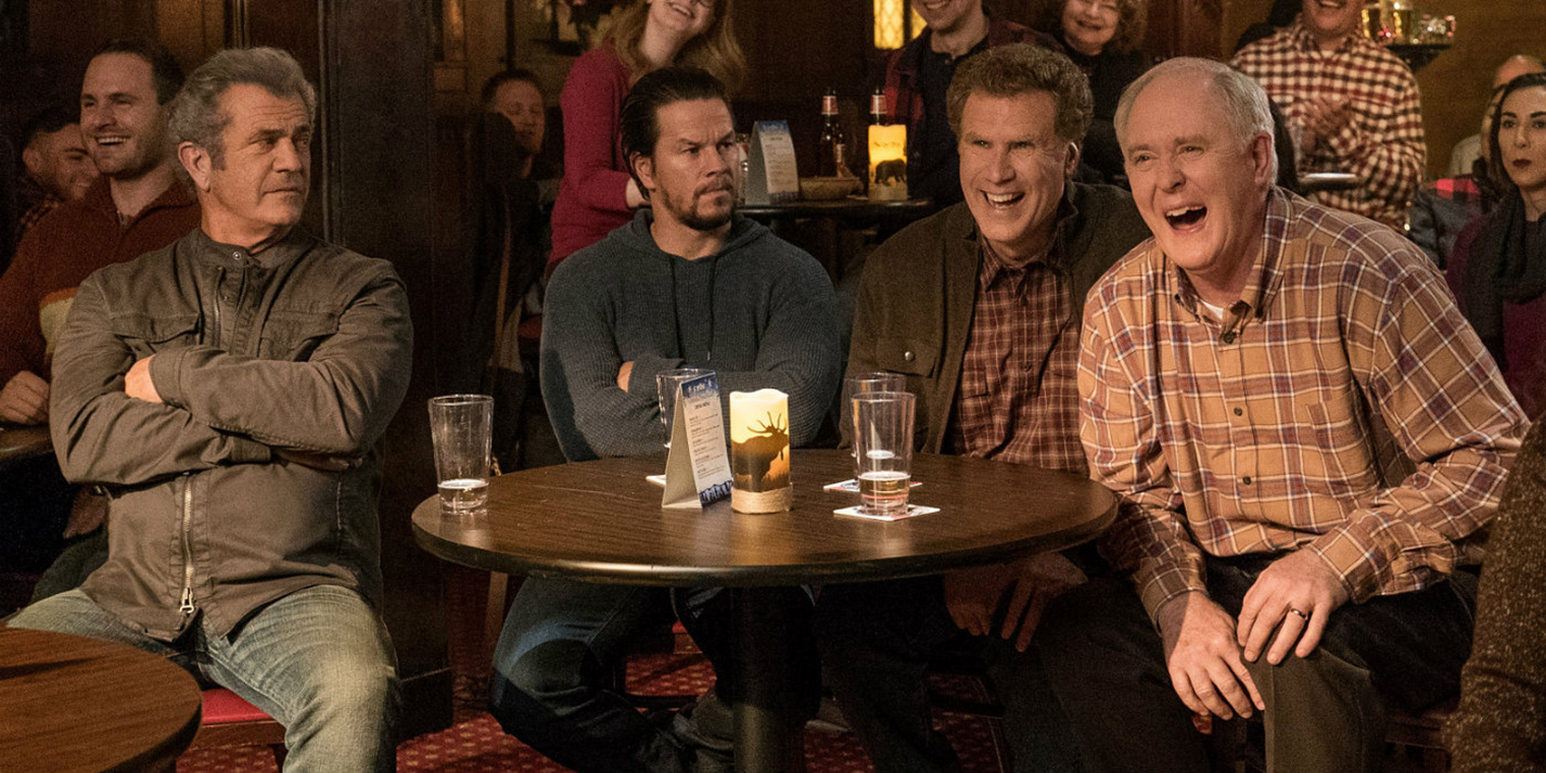 Kurt (Mel Gibson), Dusty (Mark Wahlberg), Brad (Will Ferrell) and Don (John Lithgow) sit together as they watch an improv group perform on their “dads night out” in Daddy’s Home 2.