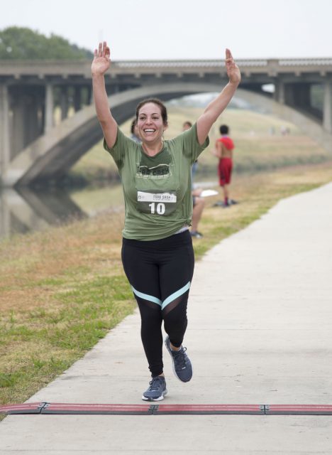 SE student Caren Garcia raises her hands in celebration of crossing the finish line. She placed 20th in the 5K race.