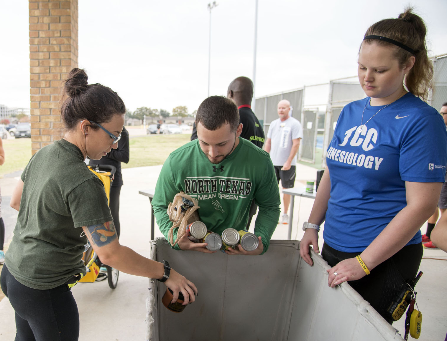 NE student Amanda Siefert and NE kinesiology workers Kenneth Gonzales and Morgan Ferguson drop off canned food donations that students were required bring to participate in the Turkey Trot.