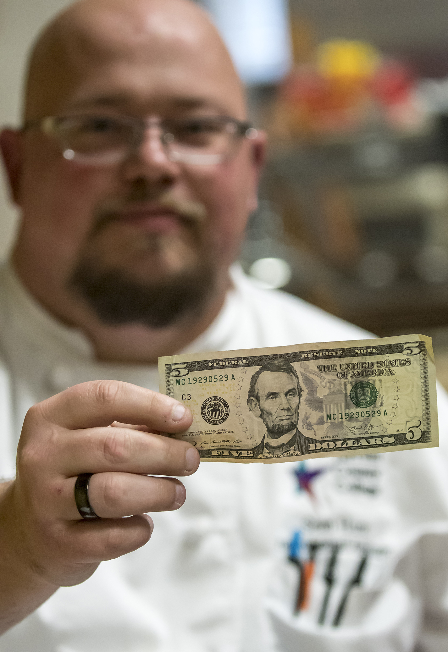 SE culinary arts instructional assistant Sean Hunt holds a $5 bill, which will buy a lunch prepared by the program.