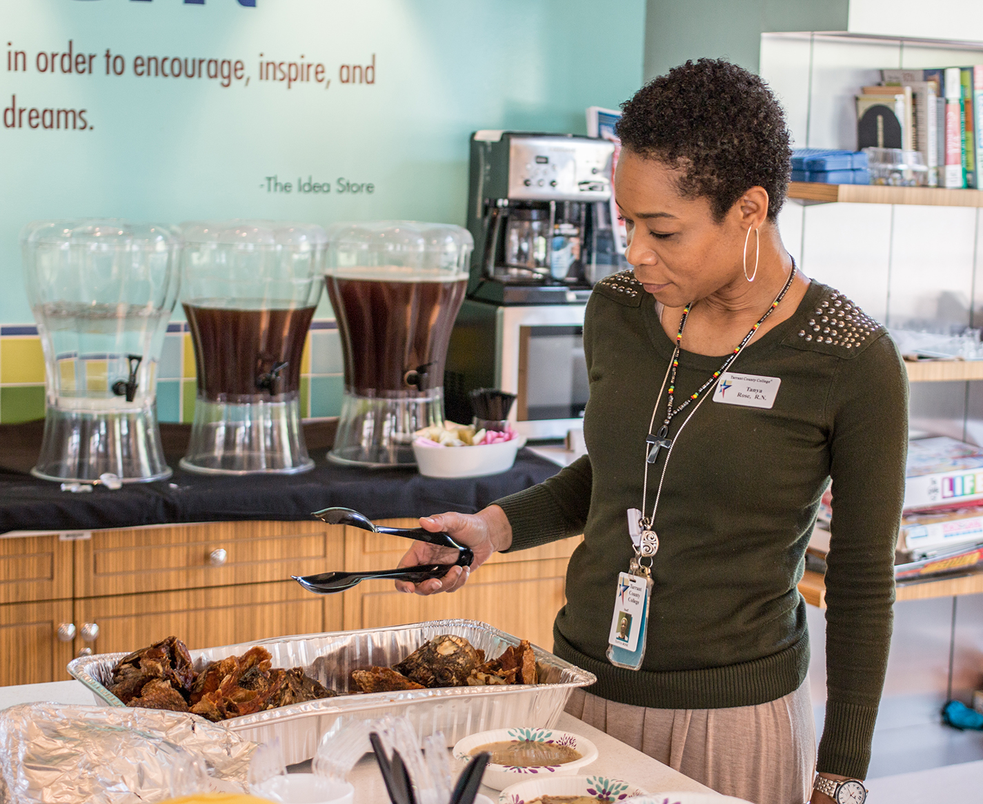 TR nursing assistant professor Tanya Rose picks up fried fish brought to the Multicultural Potluck Lunch in TR’s Idea Store April 4. Students, faculty and staff were encouraged to bring dishes from their culture.