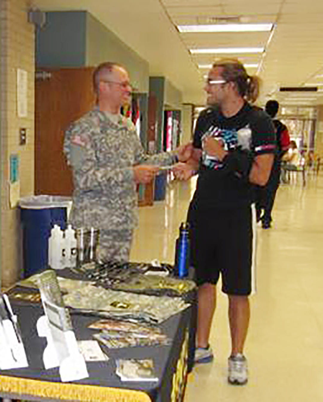 A recruiter offers a student information about military careers at a previous fair.