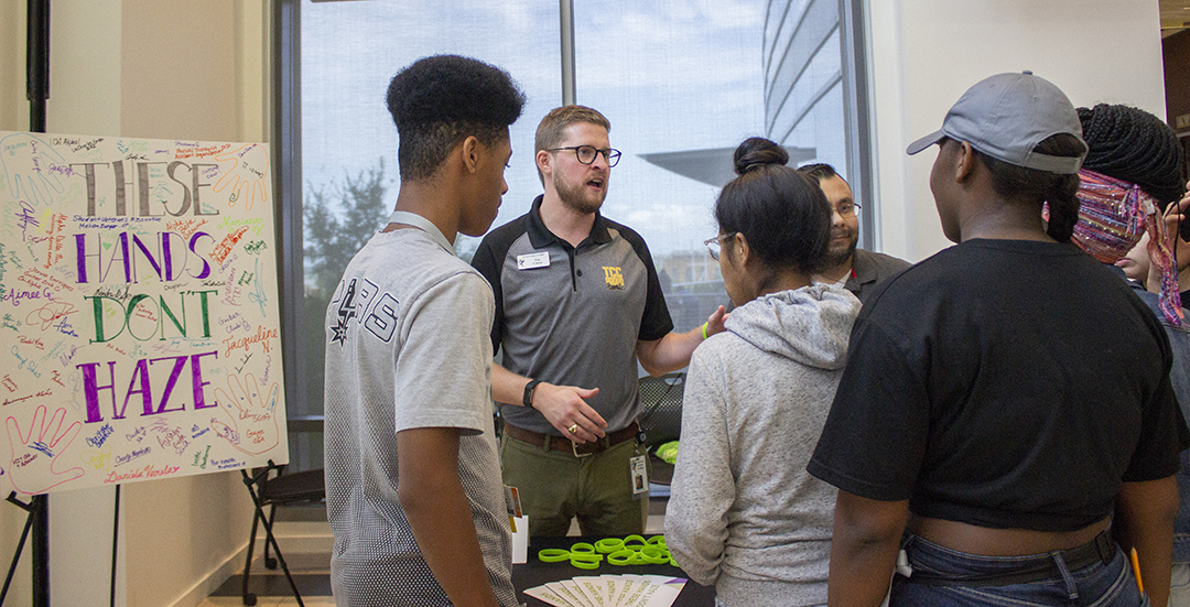 TR student support coordinator Tim Cason discusses the consequences of campus hazing with TR students at the These Hands Don’t Haze table set up on TR’s Main Street during the campus’ Club Crawl Sept. 6.
