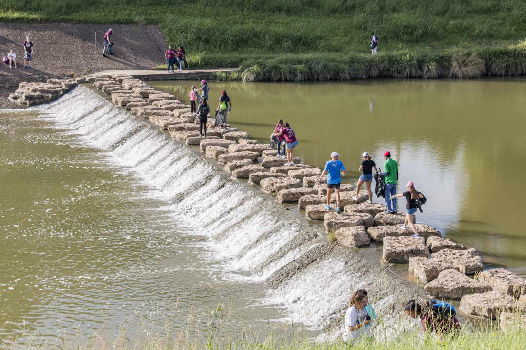 TCC students and other community members walk along the rocks across the Trinity River in Fort Worth to pick up trash during the Trinity Trash Bash on Sept. 15. Garbage and gloves were provided to all participants.