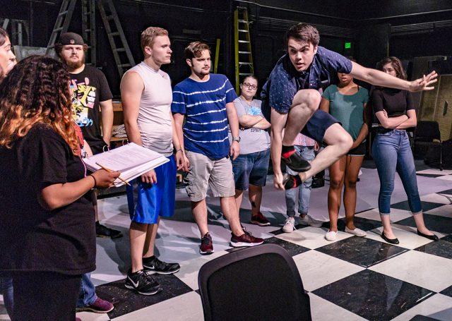 NE+student+Austin+Peake%2C+who+plays+Jesus+in+Godspell%2C+rehearses+a+scene+that+involves+him+jumping+over+his+leg+to+demonstrate+a+lesson+to+his+disciples.+The+musical+opens+Oct.+16+and+will+run+through+Nov.+1+on+NE.