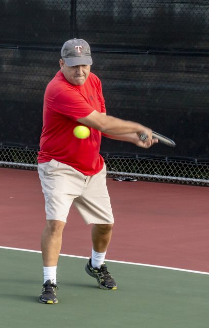 NW math instructor Alan Cazares backhands the ball during NW intramural tennis on Oct. 11.