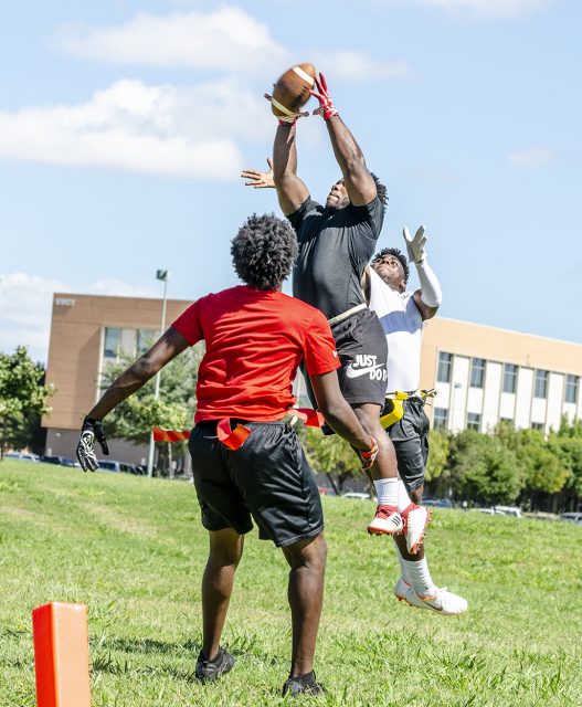 A SE student reaches for the sky to catch the ball while an opposing player attempts to intercept it during the intramural flag football championship on SE Campus.
