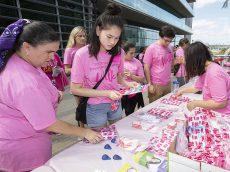 Volunteers hand out breast cancer awareness-themed gift bags to students who participated in the walk. 