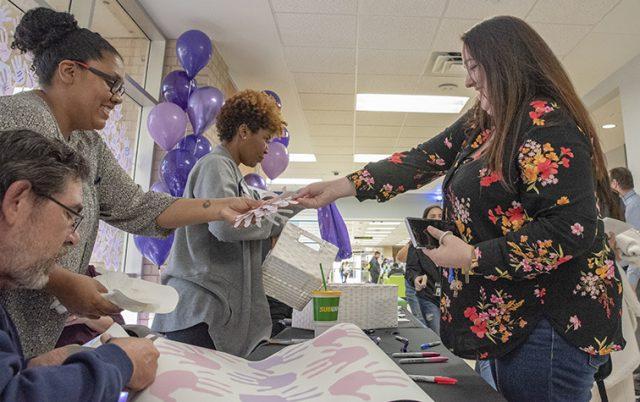 Photo by Joseph Serrata/The Collegian. NW student Denise White receives paper handprints to place on the wall as a promise to never commit domestic violence. A table was set up Oct. 22 in the WSTU breezeways for domestic violence awareness.