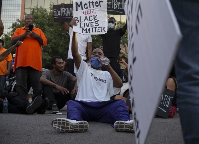 A leader of United My Justice sits down on Weatherford street, holding a sign, “No lives matter until black lives matter” in Fort Worth May 29.