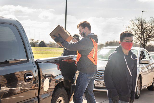 Elder White and Osmar Castino load boxes of food into the trunk of a passing pickup. The event was sponsored by Arlington Charities and Tarrant Area Food Bank. 