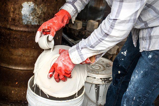 NE student Sam Watson pours glaze over his ceramic piece, gently rotating it in the other hand. He has several pieces on display in the Grapevine Tower Gallery. Photos by Azul Sordo/The Collegian