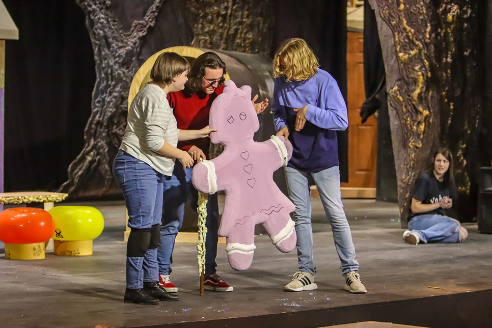 NW students Ashleigh Sommer, Trey Kelly and Connor Kaiser hold a gingerbread-shaped prop during rehearsal Feb. 22. CAMERON WEBSTER Alex Hoben/The Collegian