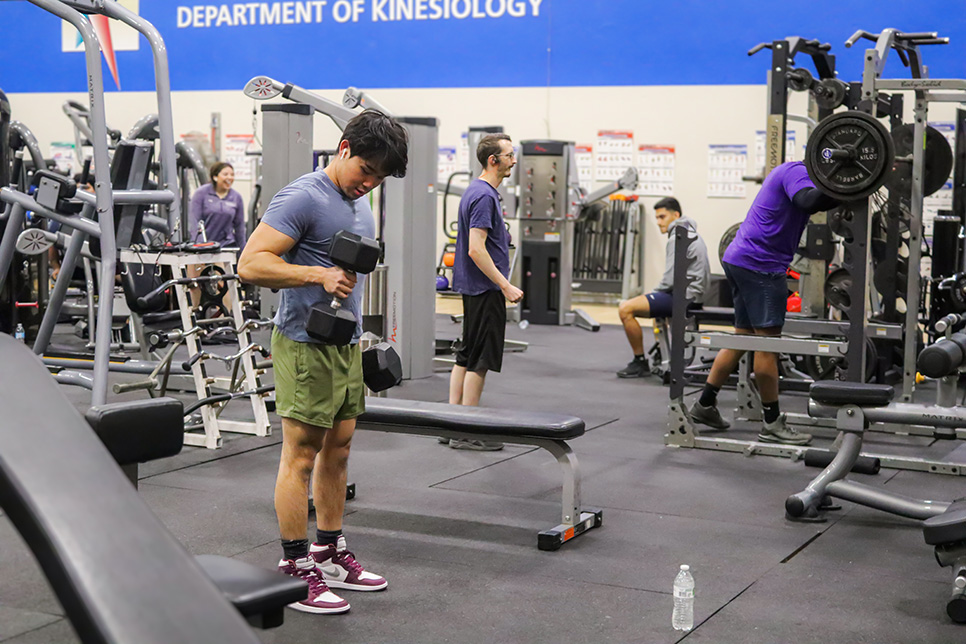 NW staff member Khoi Le does reps with dumbells provided in the NW weight room. The room is available to any student or staff member with an ID. Alex Hoben/The Collegian