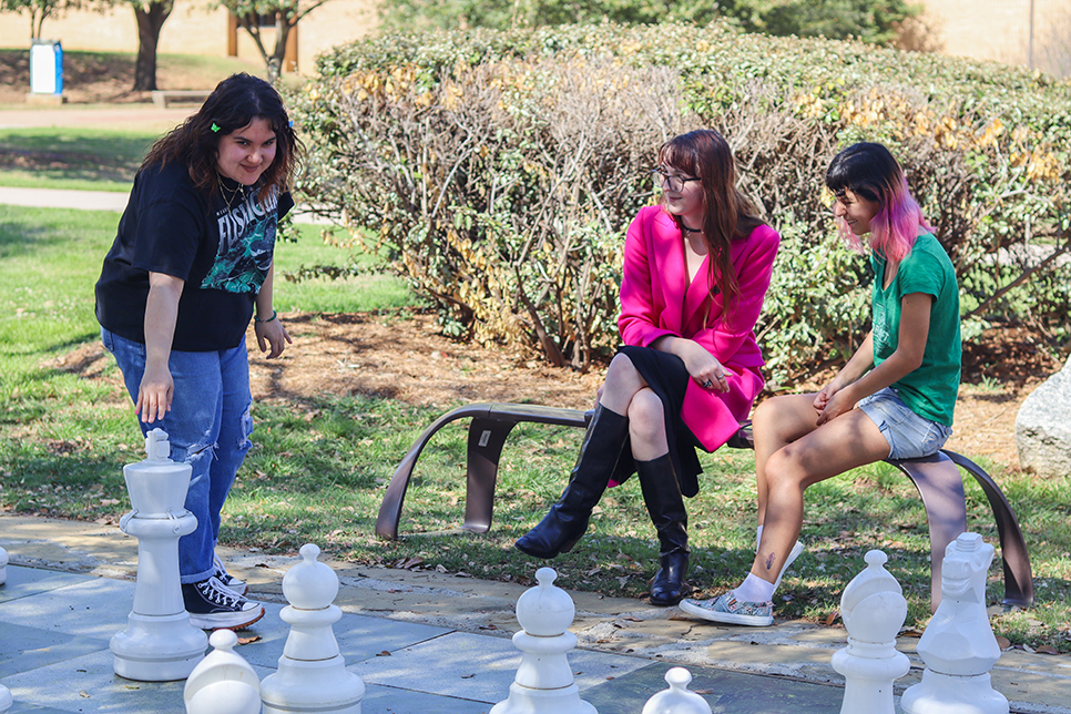 NE Pride Club members Reyna Jimenez, Jane Dubrow and Azriel Stevens play on the large chessboard outside of the NCAB building on NE Campus April 5. Alex Hoben/The Collegian