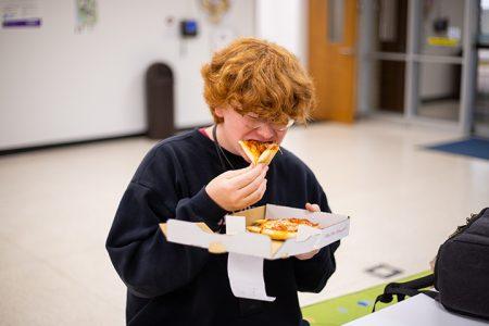 Jake Lane eating slice of pizza at Motown Pizza at NW Campus photo by Joel Solis / The Collegian