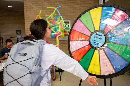 NW student Taylor Guerra spins a wheel to earn a prize at the Walsh Library booth at Northwest Fest.