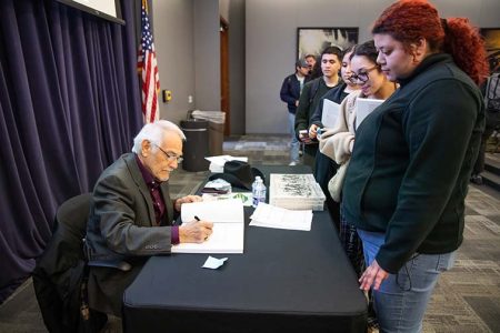 Andres Tijerina hands his book to TR student Valeria Najera attending the Cowtown event in the energy auditorium on TR Campus. The event featured both him and Judge Manuel Valdez. Joel Solis/The Collegian