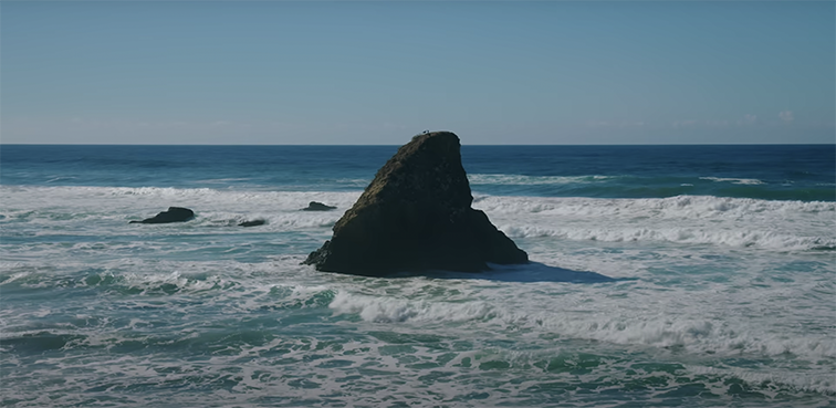 A large rock sits on the shore among ocean waves in a YouTube music video for Canadian musician Mac DeMarco’s instrumental album “Five Easy Hotdogs.” Photo courtesy of YouTube