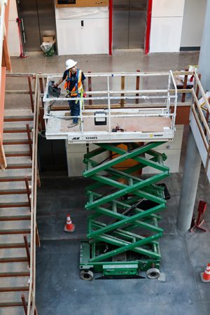 A construction worker uses an electric scissor lift to access the second level of the NW05 building. The building is currently still an active work zone. Alex Hoben/The Collegian