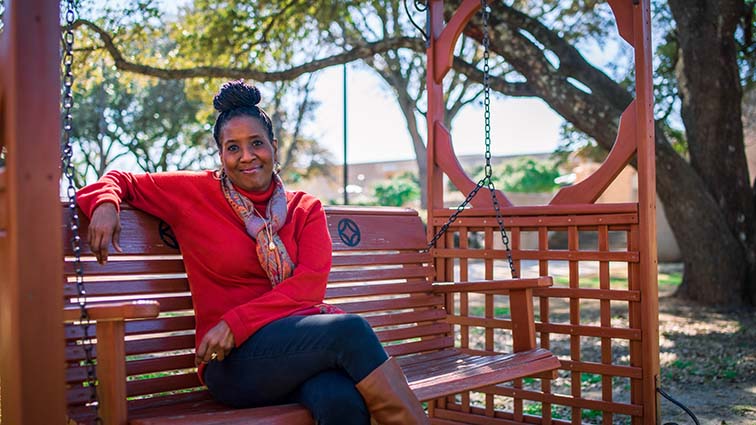 NE associate English professor and TCC chair member Shewanda Riley poses on a swinging bench on NE Jan. 27. Her office is in NFAC. Photos by KJ Means/The Collegian