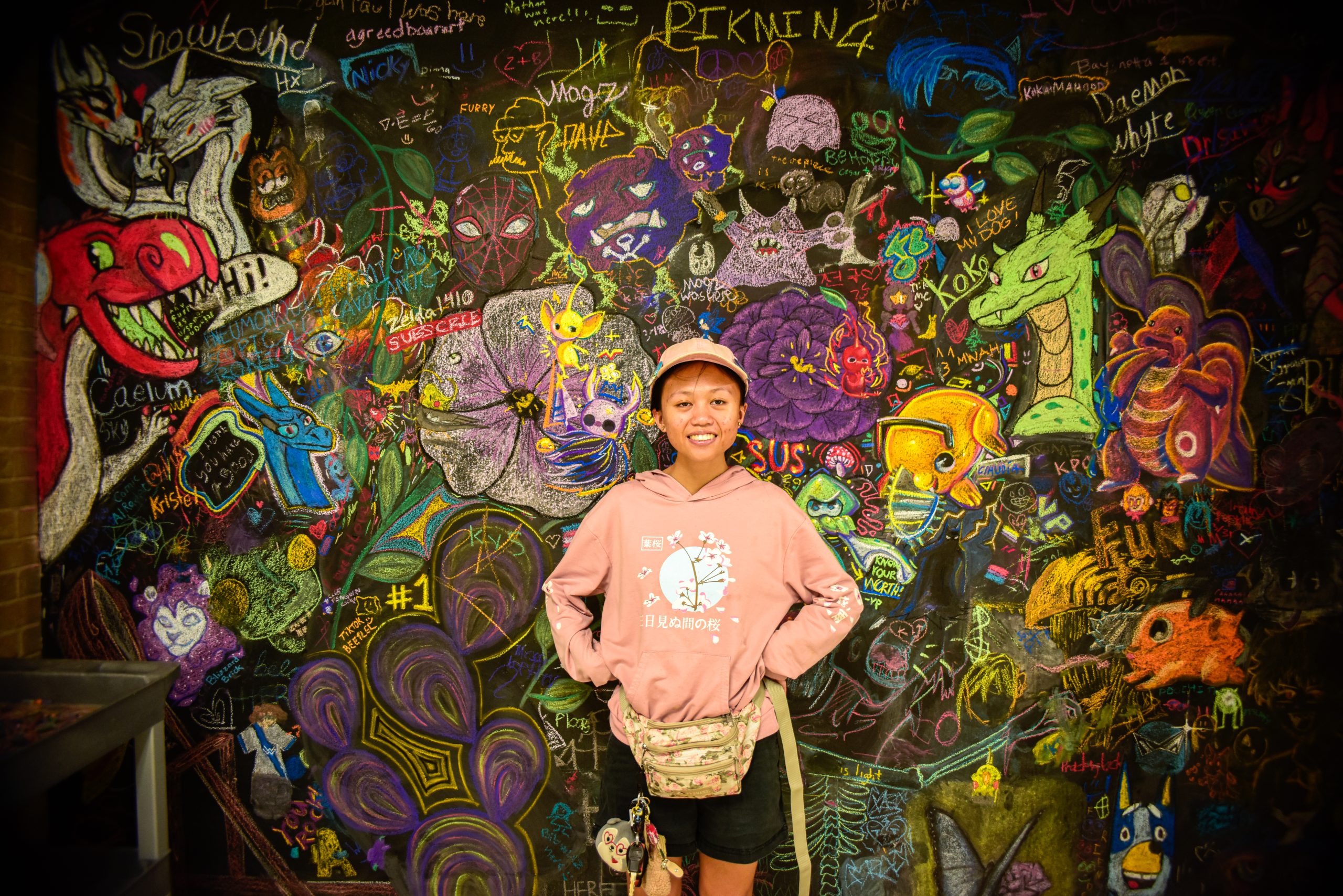 Alex Hoben/The Collegian NE student Mena Kennedy stands in front of the chalkboard wall that is available for students and staff to draw on in NFAB.