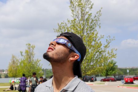 Hope Smith/The Collegian NW student Alejandro Vega observes the sun at 25% eclipse with the special viewing sunglasses given out by the NW earth science department table at the viewing party. This is his first eclipse, and he first found out about it while browsing Instagram.