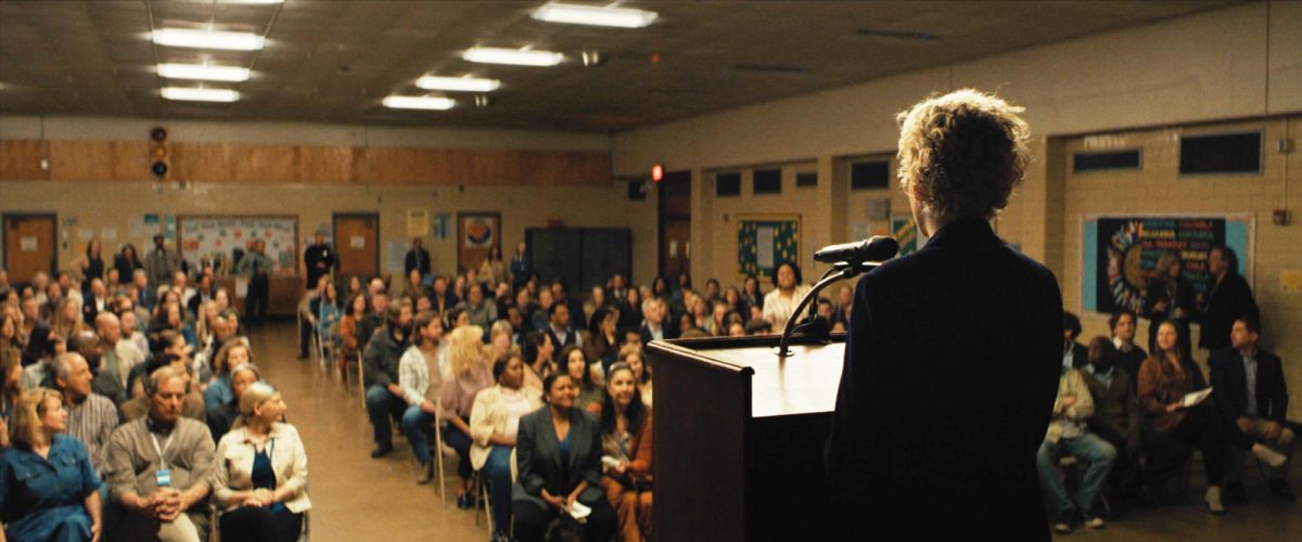 Julia Garner, who plays Justine Gandy in “Weapons,” addresses room full of parents about the sudden disappearance of their 
children at 2:17 a.m.