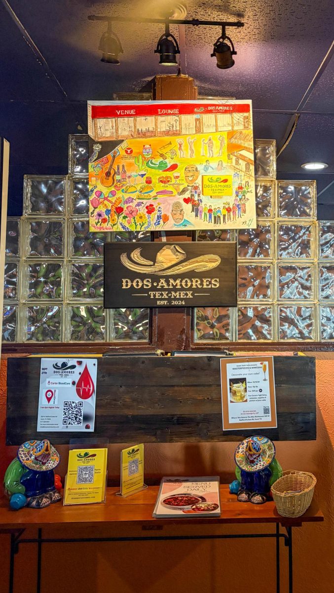 The front entrance of Dos Amores is adorned with a sign above the logo detailing art about the customers, servers and food surrounding the culture of Mexican food.
