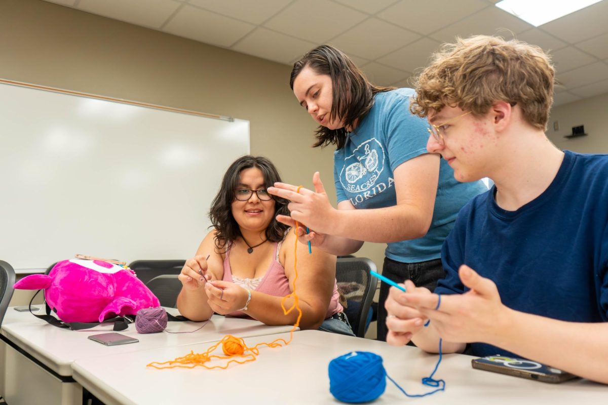 Needle Arts Club senator and NE student Emily Proctor teaches Karisma Tovar and Caleb Joiner how to make plush animals.
