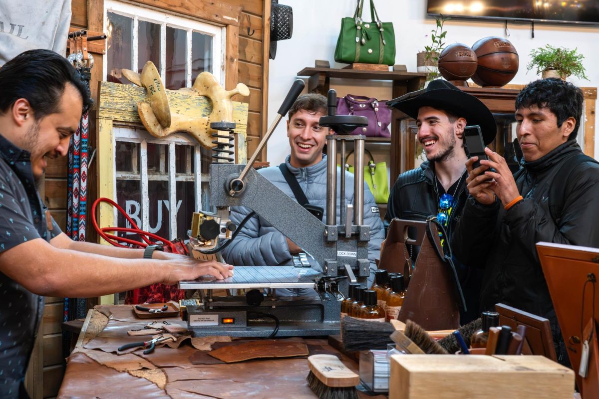 Tomás Nielsen, Facundo Capra and Leo Valviviezo watch Will Leather Goods store manager Oscar Martinez emboss leather keychains for them free of charge.