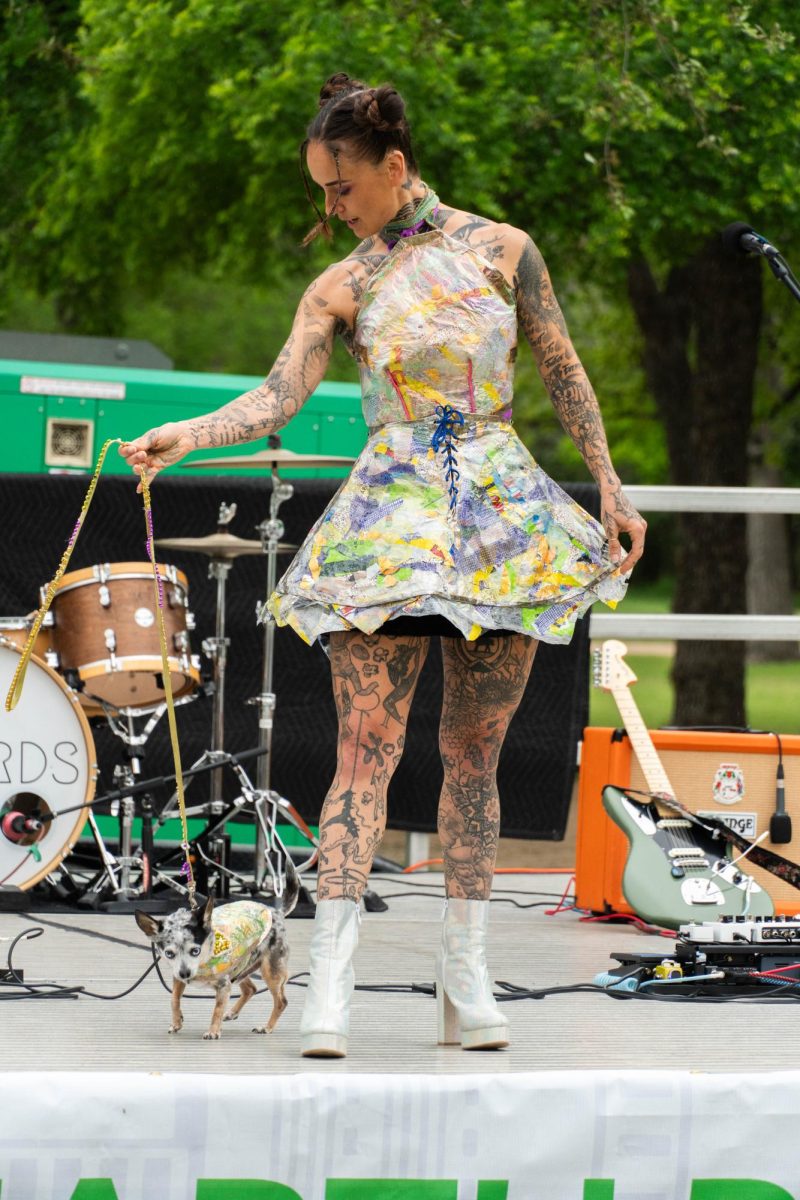 Melynda Lowe and her dog on the stage showing off her dress made from fabric scraps and clear pearlescent plastic.