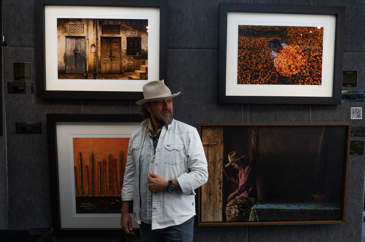 A portrait with Greg Davis posed in front of some of his work, including one of this year’s award winning photograph on the top right.