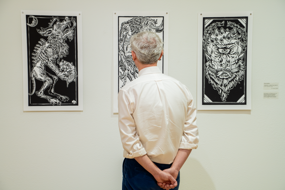 TR instructor Andrew Giles views three works of art by SE instructor Martin Molina. From left to right the woodcut relief prints are titled “Chupacabra,” “Minotaur” and “Cyclops,” Sept. 19.