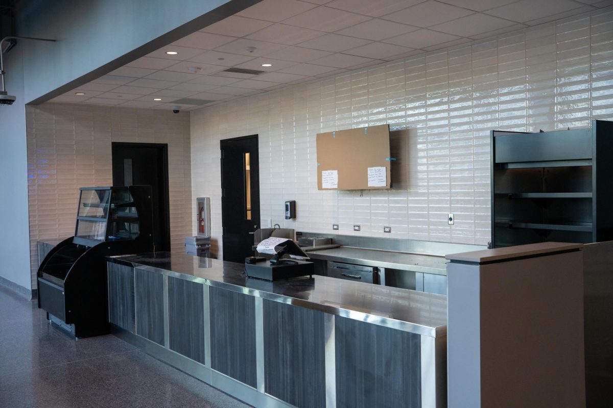 NW cafeteria shelves lay empty as the faculty prepares to open it. Paper signs and sharpie text informs readers that interacting with the technology may cause a delay in its opening. 